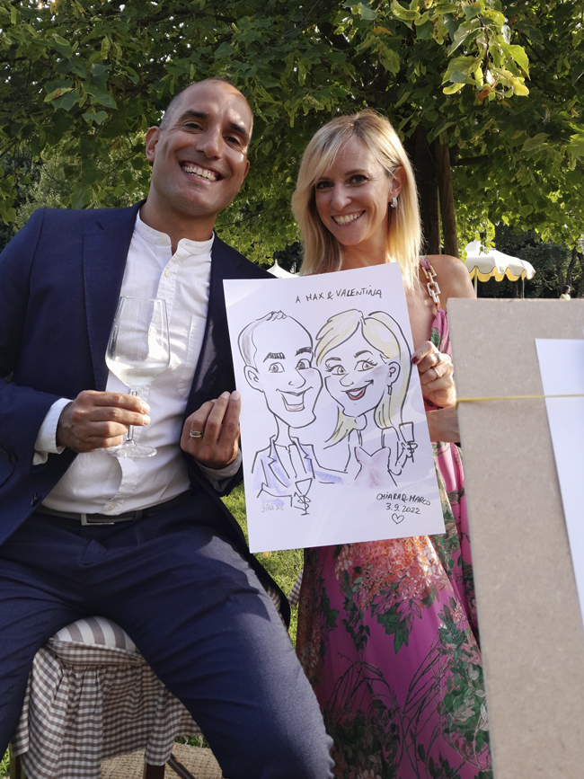 Una coppia di fidanzati mostra la propria caricatura appena ricevuta durante il ricevimento di matrimonio