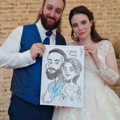 una coppia di sposi mostra la propria caricatura appena disegnata durante il ricevimento